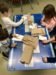 students around table tinkering with items inside of brown bags